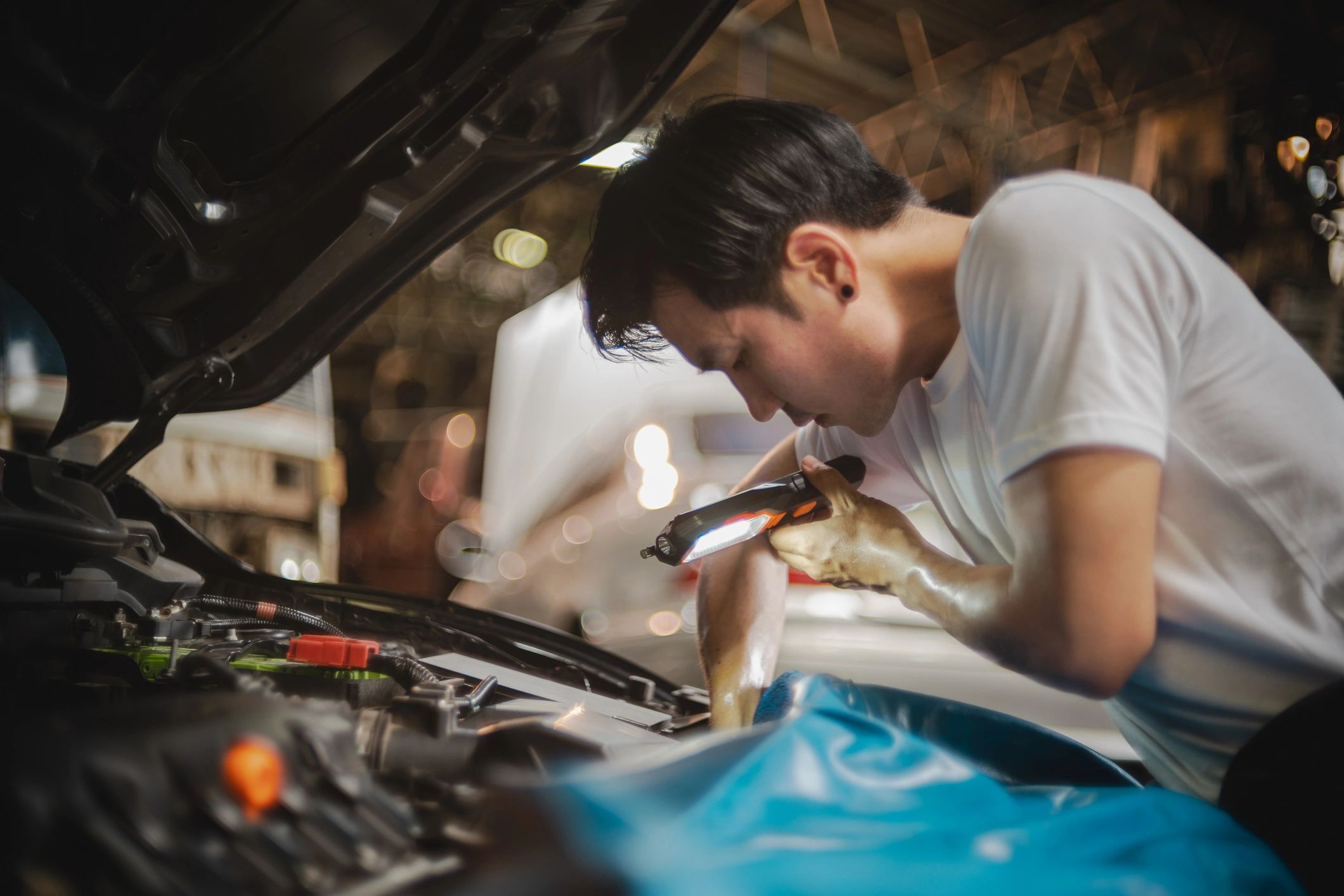 Mechanic inspecting a vehicle engine in a repair bay