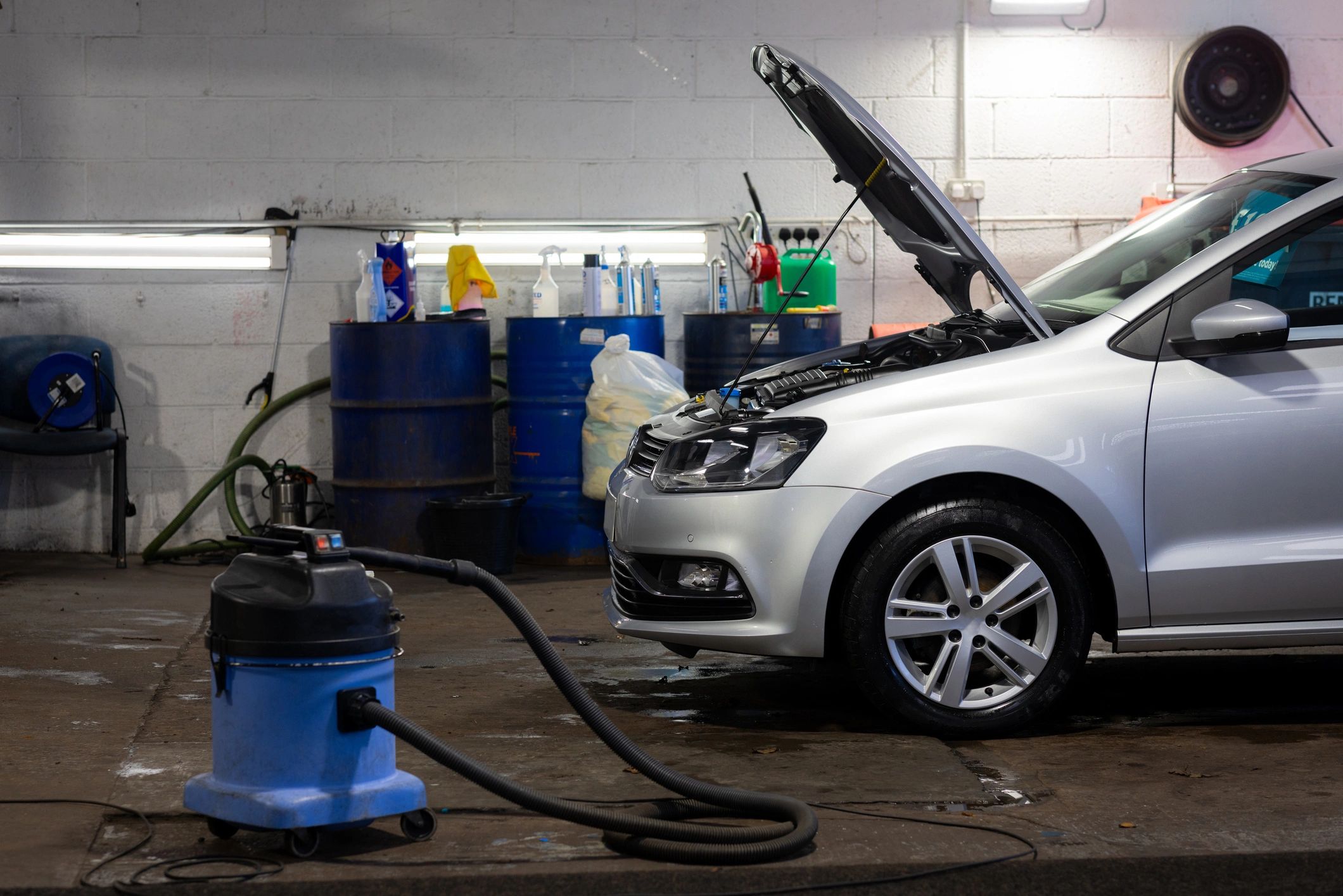 Silver car being serviced inside an auto repair garage